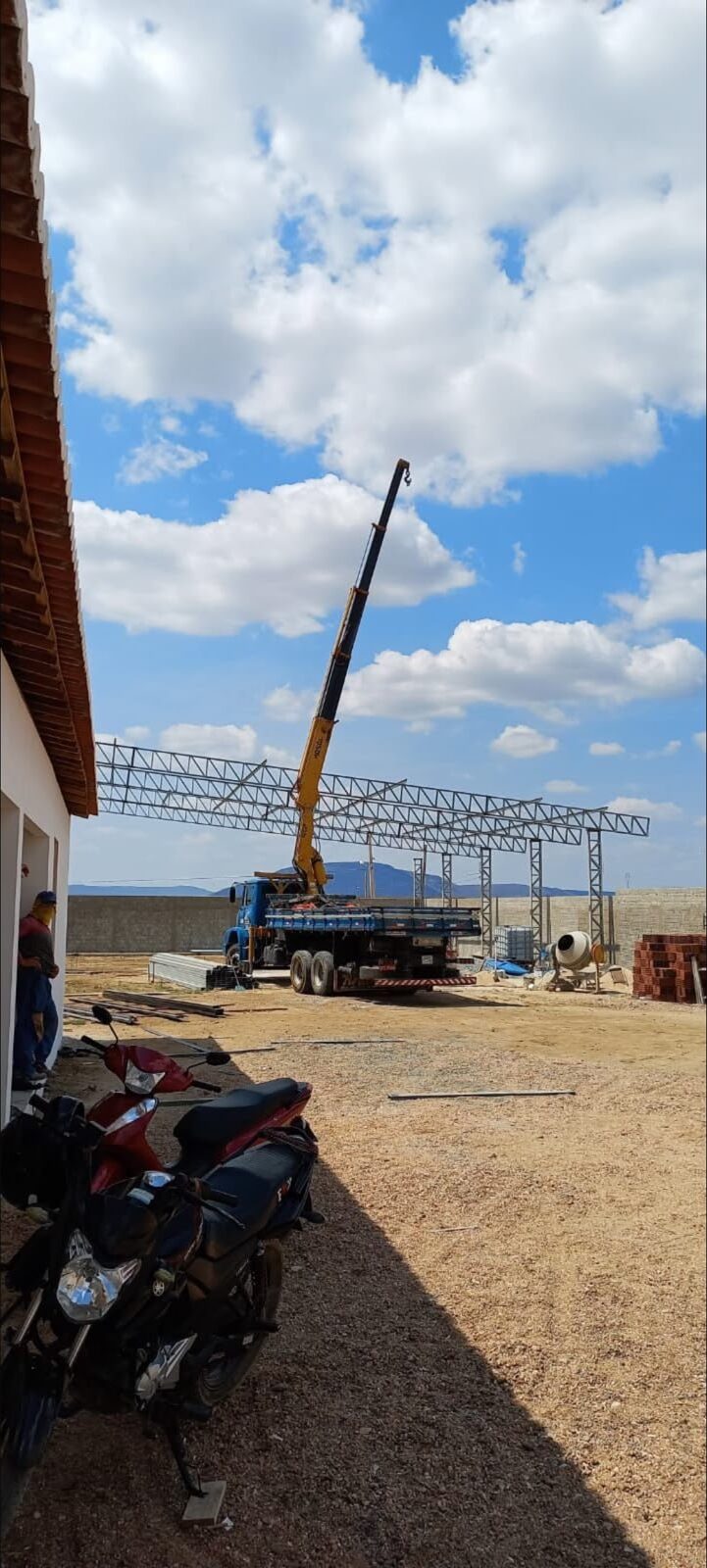 Caminhão munck posicionando estrutura metálica em obra